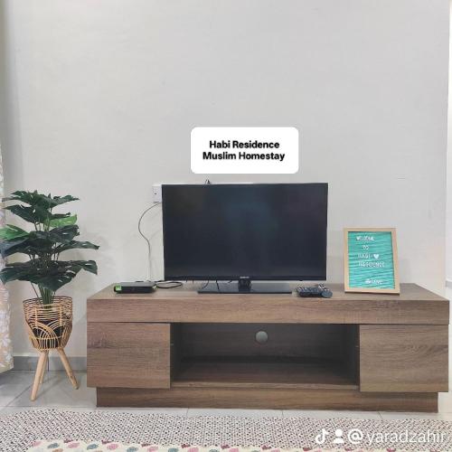 a television on a wooden entertainment center in a living room at Homestay HABI Residence in Kepala Batas