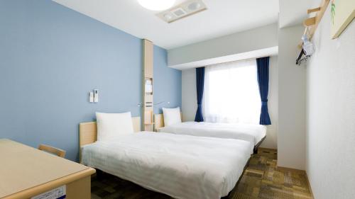 two beds in a room with a window at Toyoko Inn Tokyo Machida eki Odakyu sen Higashi guchi in Machida