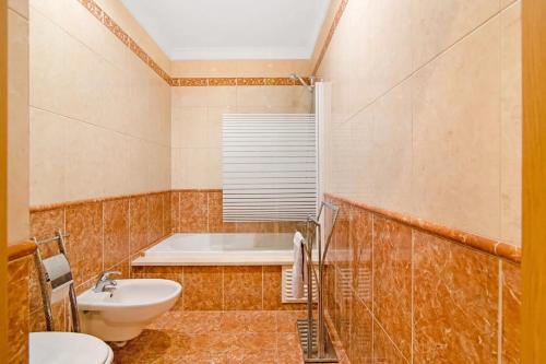 a bathroom with a toilet and a tub and a sink at Almancil Park Apartment in Almancil