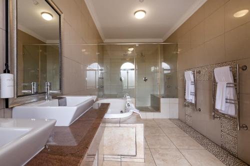 a bathroom with two sinks and a tub and a shower at Basdenwood Hotel in Centurion