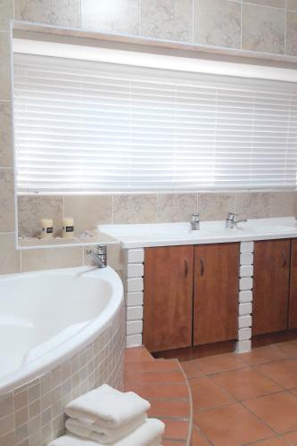 a bathroom with a tub and a sink at Sunset on Silver Beautiful self catering Studio apt in Roodepoort