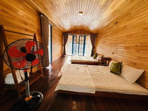 a wooden room with two beds and a fan at Maisonson Resort in Dương Kê
