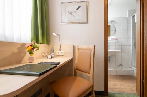 a room with a desk with a laptop and a bathroom at Hotel Zur Traube in Velbert