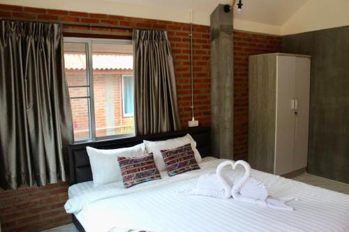 a bedroom with a large white bed with two swans on it at MatanaCafe&Resort in Ban Bo Nam Khao