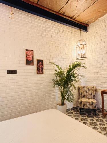 a white brick wall with a chair and a plant at Asmi by Beal's Farm in Jaipur