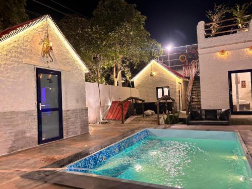 a swimming pool in front of a house at night at Asmi by Beal's Farm in Jaipur