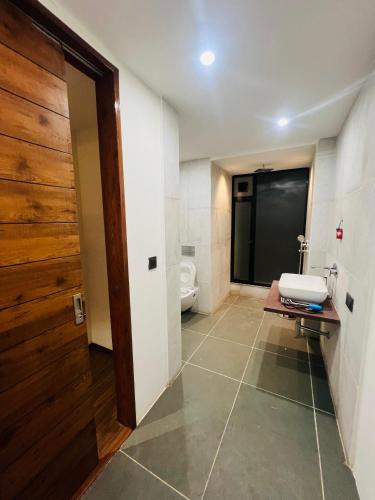 a bathroom with a toilet and a wooden door at Weekend villa in Rajkot