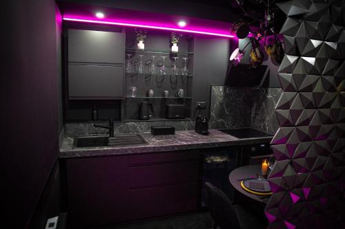 a kitchen with a purple light above a counter at L'Eclipse - Exceptional SPA Suite, sauna and hammam in Douai