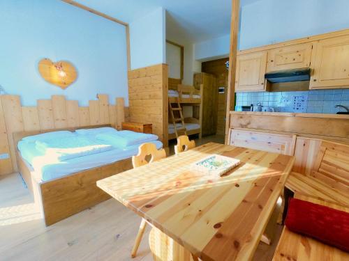 a room with a bed and a table and a kitchen at Valles Vacanze - ski in & ski out in Falcade