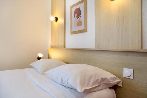 a bedroom with a bed with two white pillows at Sweetly Isatis Mérignac Hôtel de ville in Mérignac