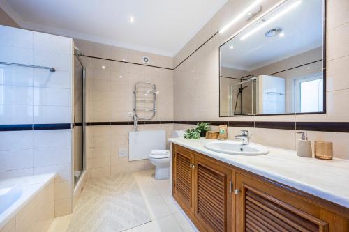 a bathroom with a sink and a toilet and a mirror at Burgau Sea View, Beach & Pool Villa in Budens
