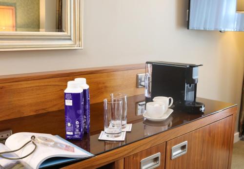 a table with a coffee maker and glasses on it at The Rose Hotel in Tralee