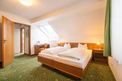 a bedroom with a large bed with white sheets at Hotel Zur Traube in Velbert