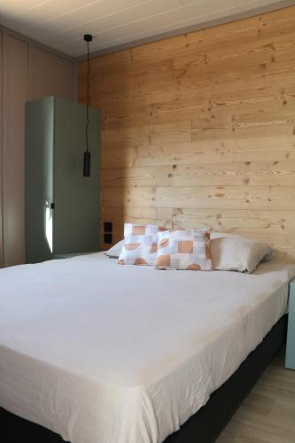 a bedroom with a white bed with a wooden wall at Chalet Confort 49 in Rivières