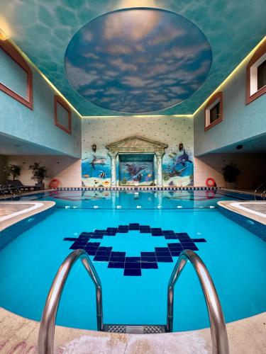 a large swimming pool with a large painting on the ceiling at Petra Canyon Hotel in Wadi Musa