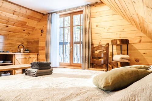 a bedroom with wooden walls and a bed with a window at Vējciems in Liepene