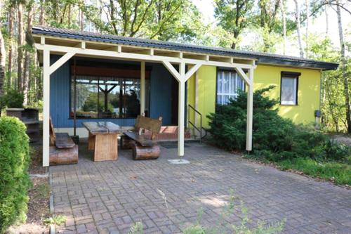 a pavilion with a table and a bench in front of a house at Themencamping Grünewalder Lauch in Grünewalde