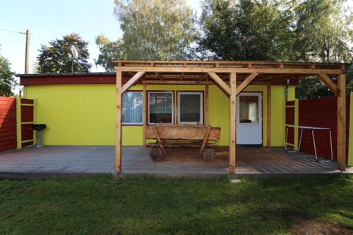 a small yellow house with a deck with awning at Themencamping Grünewalder Lauch in Grünewalde