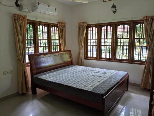 a bedroom with a bed in a room with windows at Veranda Villa in Angamaly