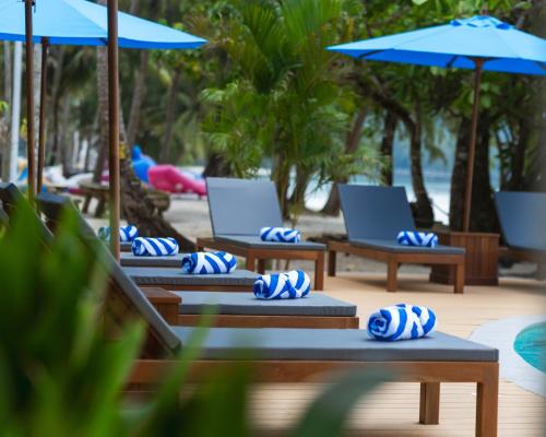 a row of lounge chairs with umbrellas on a beach at Mafiya Resort in Koh Rong Island