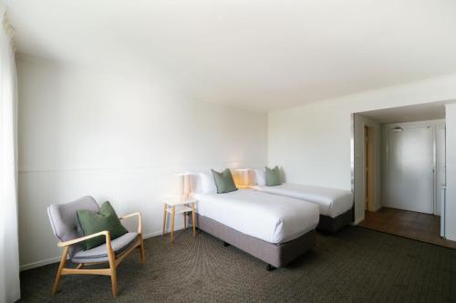 a hotel room with two beds and a chair at The Leea, Darwin in Darwin