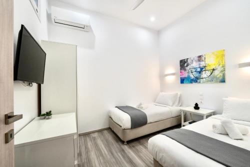a bedroom with two beds and a flat screen tv at Central Suites Aegina 2 in Egina
