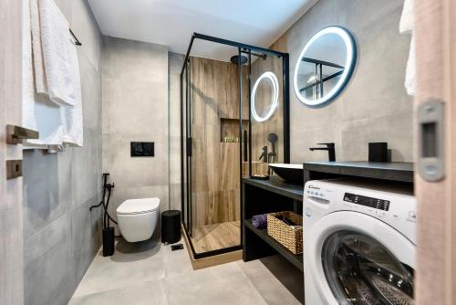 a bathroom with a toilet and a washer and dryer at Central Suites Aegina 2 in Egina