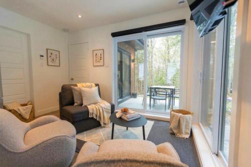 a living room with a couch and chairs and a table at Mini Chalet Assinie Spa Privé, Nature & Golf in Brownsburg