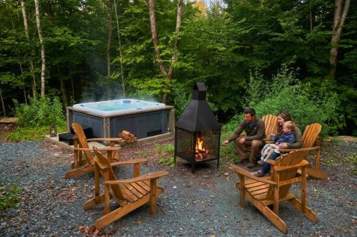 a group of people sitting in chairs around a campfire at Mini Chalet Assinie Spa Privé, Nature & Golf in Brownsburg