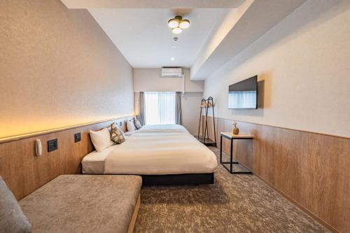 a hotel room with two beds and a tv at Apartment Hotel 11 Nambaminami 5 in Osaka