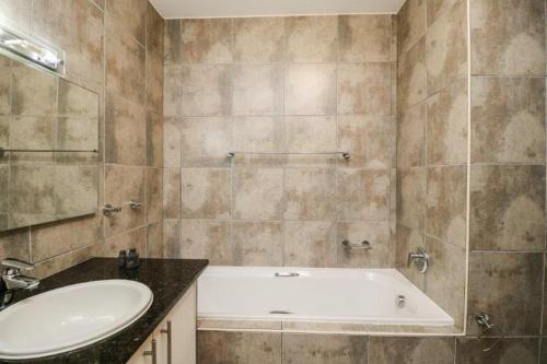 a bathroom with a white tub and a sink at 302 Hibernian Towers Self Catering Accommodation in Strand