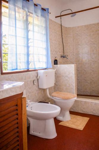 a bathroom with a toilet and a sink and a window at Elephant Villa Diani in Ukunda