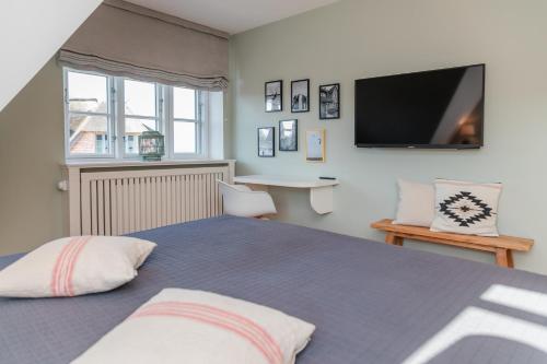a bedroom with a large bed with a tv on the wall at Waaster Bob in Oldsum