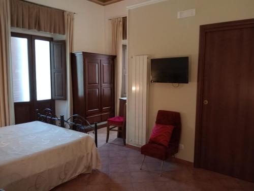 a bedroom with a bed and a tv and a chair at Lunamuta b&b in Cetraro