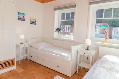 a white room with a bed and two windows at Tills Hüs in Utersum