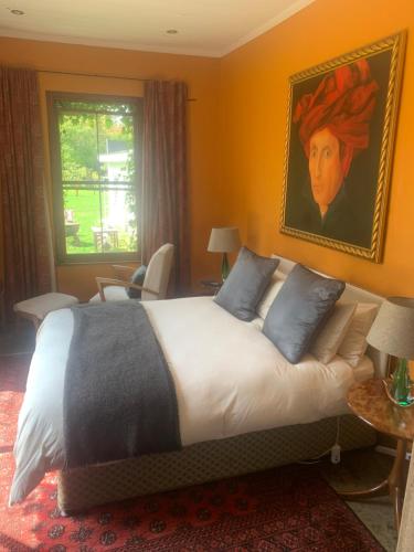 a bedroom with a large bed with a painting on the wall at The Gables Guest House in Belfast