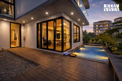 a house with a swimming pool in front of it at StayVista at Arabella with Pool & Lawn in Colva