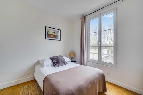 a white bedroom with a bed and a window at Charming Apartment 2BR 4P - Saint-Cloud in Saint-Cloud