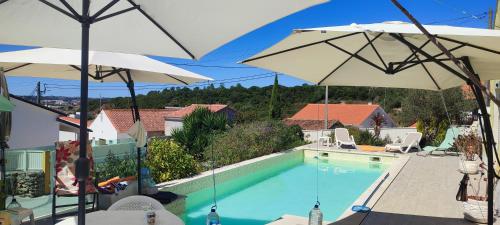 a swimming pool with two umbrellas on a house at Blue Zoon Alcobaça 2p in Carrascal