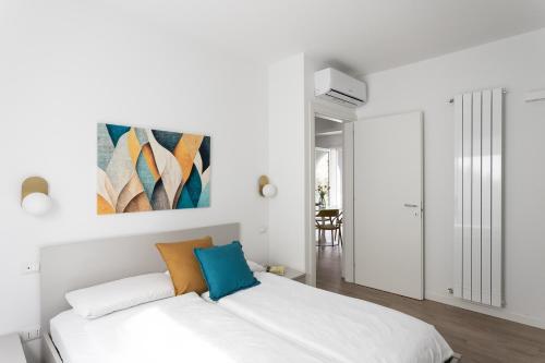 a white bedroom with a bed and a painting on the wall at Maison Bellini 2 in Toscolano Maderno