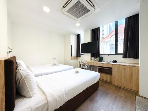 a hotel room with two beds and a desk at Aura Hotel Mackenzie in Singapore