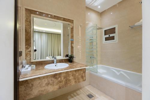 a bathroom with a sink and a tub and a mirror at Topaz Serviced Apartments in Riyadh