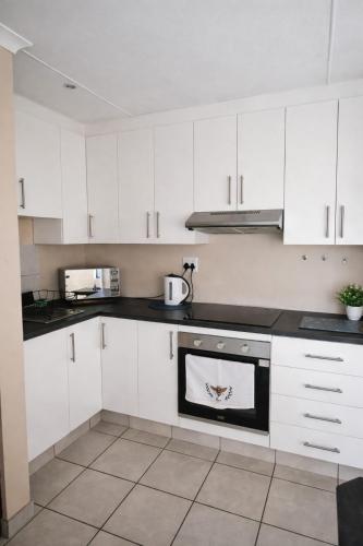 a kitchen with white cabinets and a stove top oven at Honey Cove in Mossel Bay