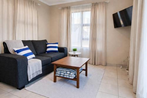 a living room with a couch and a table at Honey Cove in Mossel Bay