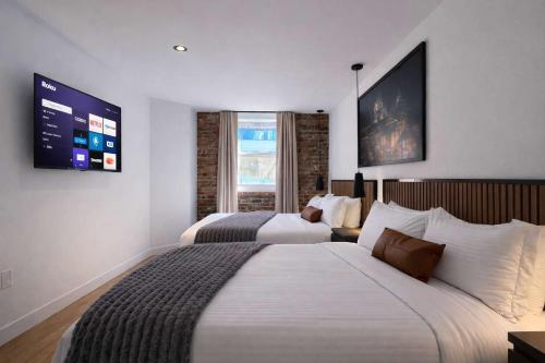 a hotel room with two beds and a flat screen tv at Room with 2 Queen-Size Beds Downtown Quebec in Quebec City