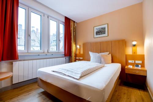 ein Schlafzimmer mit einem großen weißen Bett und roten Vorhängen in der Unterkunft Hotel Alter Kranen in Würzburg