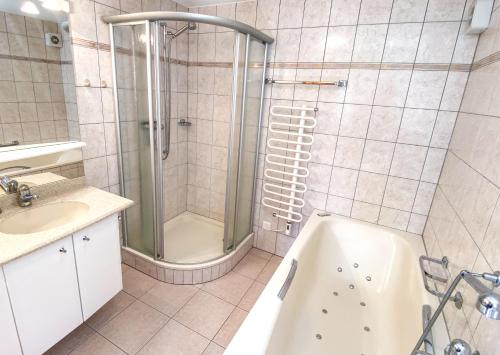 a bathroom with a shower and a tub and a sink at Chalet Charis in Bellwald