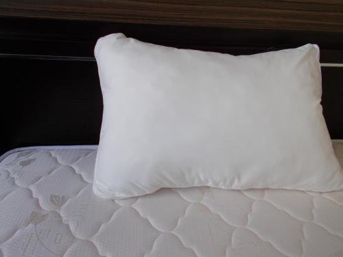 a white pillow sitting on top of a bed at Hotel Matsuyama Hills in Matsuyama