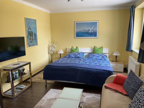 a bedroom with a blue bed and a couch at Ferienapartment Hartung in Heikendorf