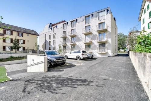 a parking lot with cars parked in front of a building at MOOI Apartments Biel in Biel